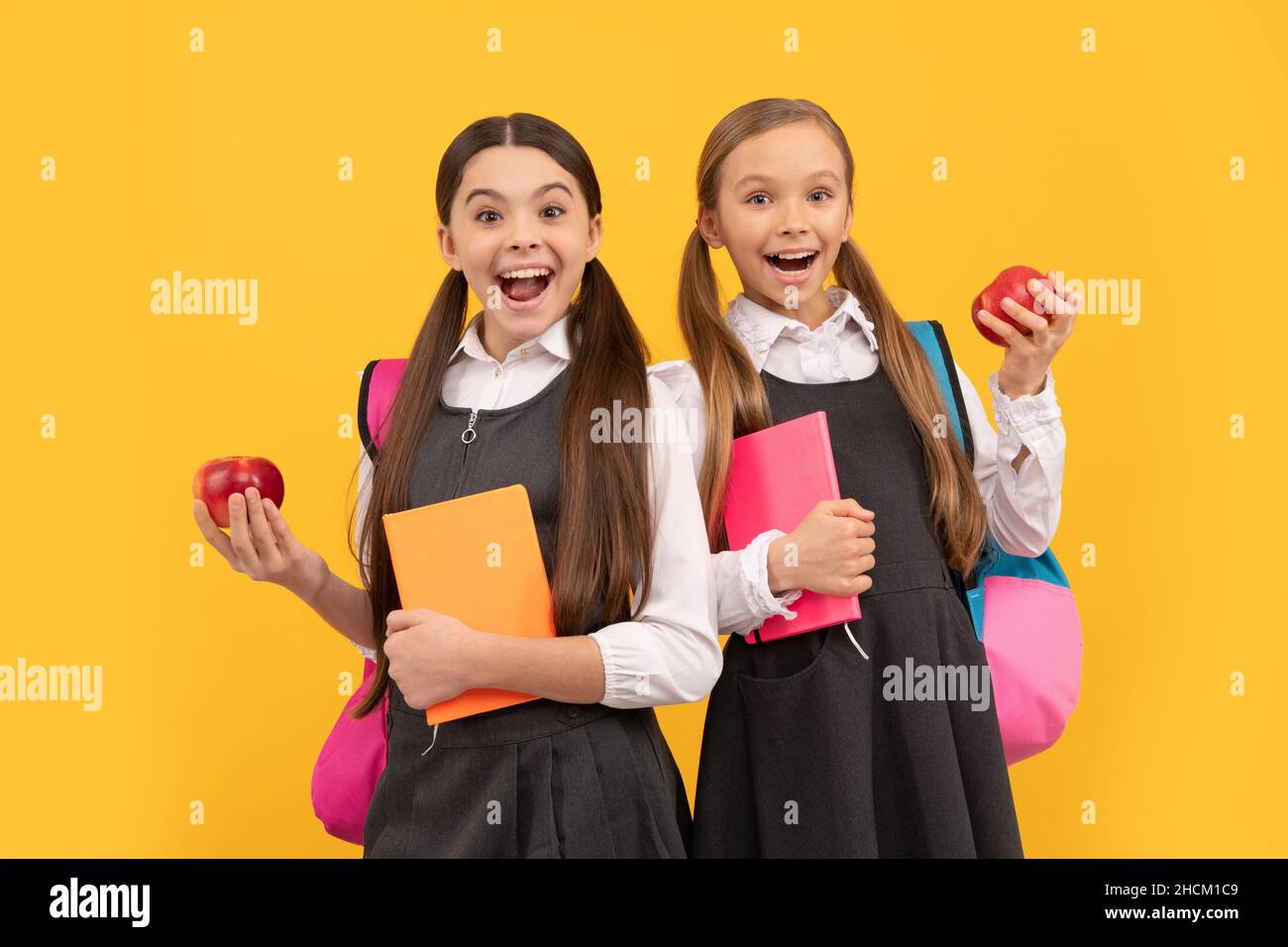 Happy kids in school uniforms hold books and apples for healthy eating school meal, snack Stock Photo