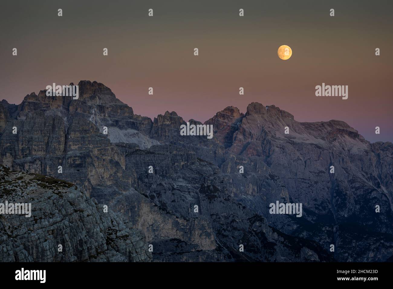 Moonrise at dusk over the Croda da Campo and Monte Camperdelle  mountains of the Sexten Dolomites, Belluno, Italy Stock Photo