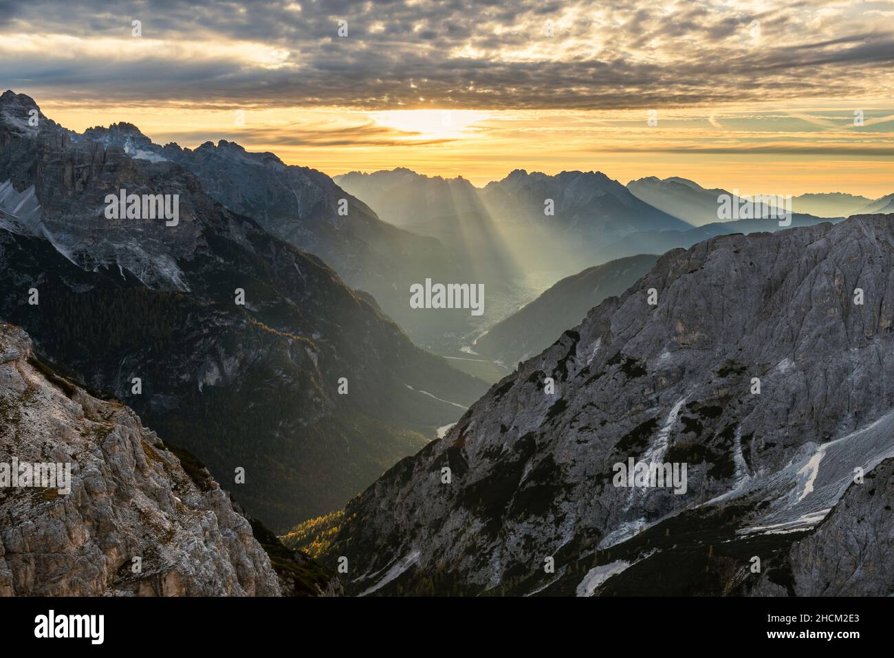 The morning sun sends rays of sunshine through the clouds onto the Valley of Ansiei and the Sexten Dolomites in autumn, South Tyrol, Italy Stock Photo