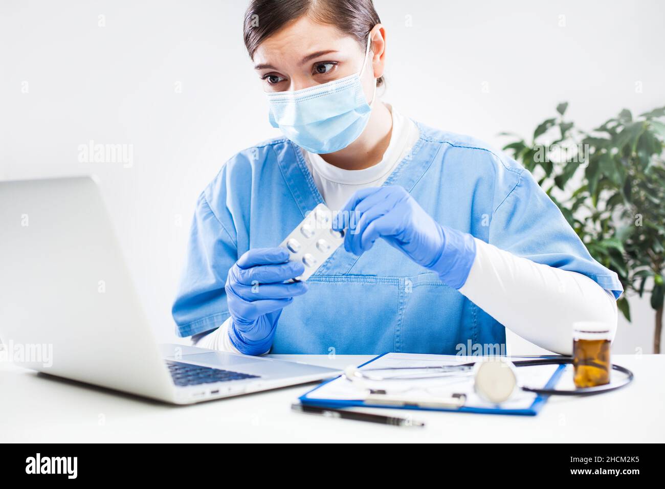 Young NHS female caucasian GP doctor sitting at office desk,wearing