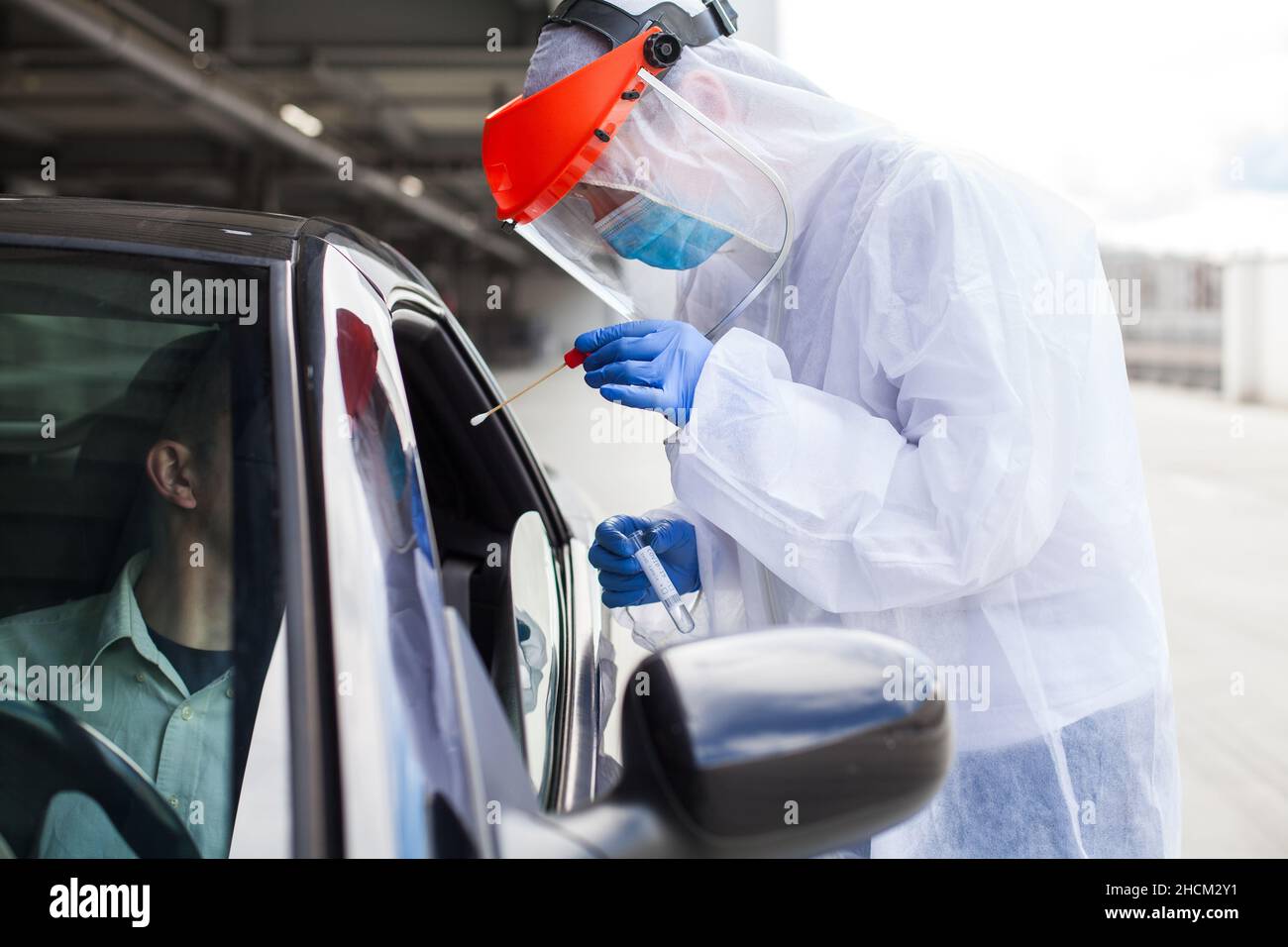 Medical healthcare worker dressed in white full protective gear,wearing face mask,protective gloves and face shield,healthcare technician collecting Stock Photo