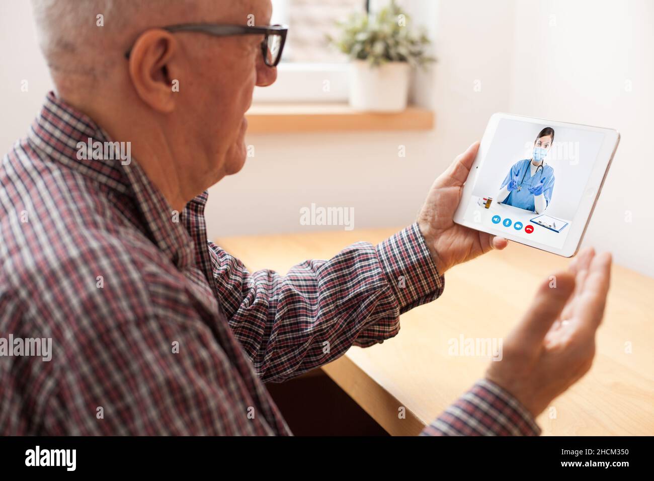 Elderly man talking to female doctor over tabled pad,concept of online on-demand medical help using video calling app,remote distance conversation Stock Photo