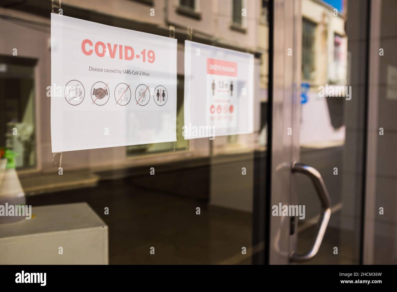 Paper notice on glass window of a store or public office informing people to follow the COVID-19 SARS-CoV-2 rules and guidelines,social distance Stock Photo