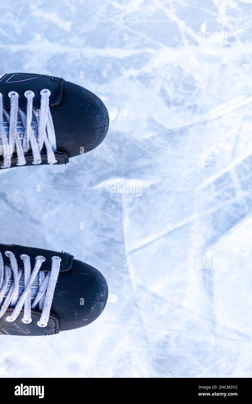 A pair of hockey skates with laces on frozen ice rink closeup. Ice skating or playing hockey in winter. ice and legs and copy space over ice backgroun Stock Photo