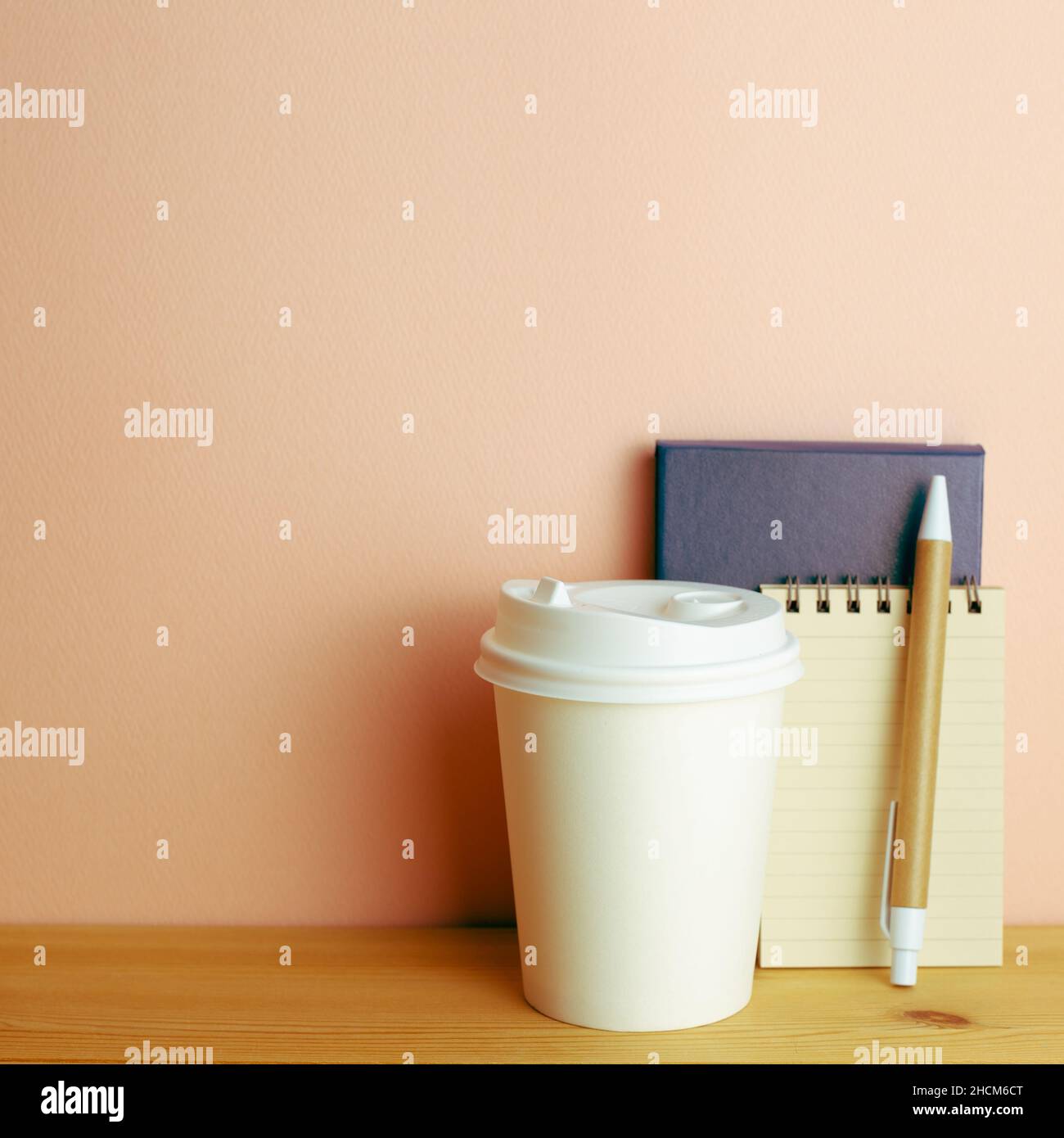 Notebook, pen, paper coffee cup on wooden desk. pink wall background. workspace Stock Photo