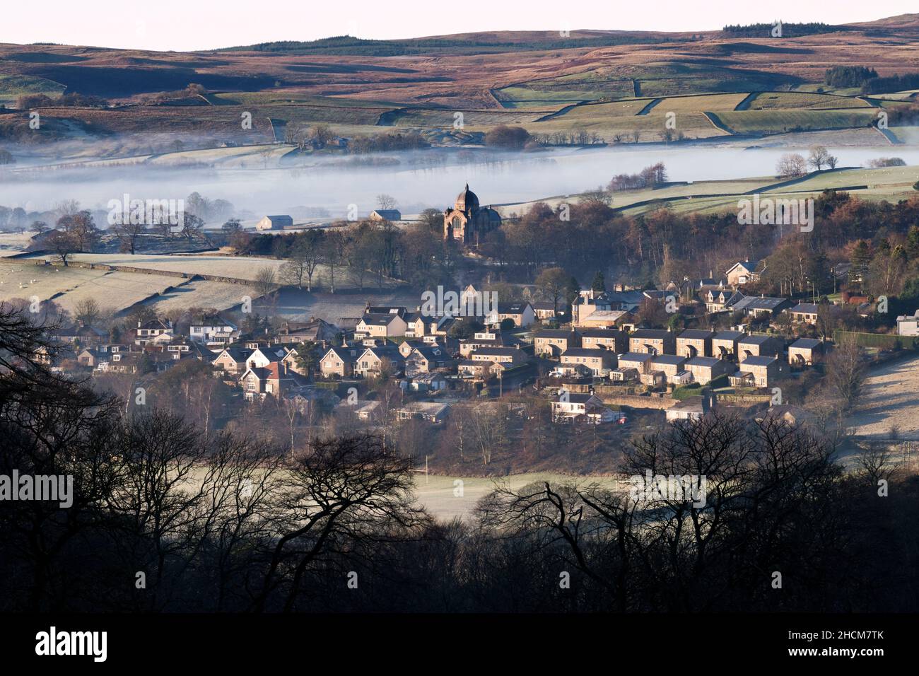 Winter temperature inversion, with low cloud over the Yorkshire Dales village of Giggleswick. The dome of Giggleswick School Chapel is  seen centre. Stock Photo