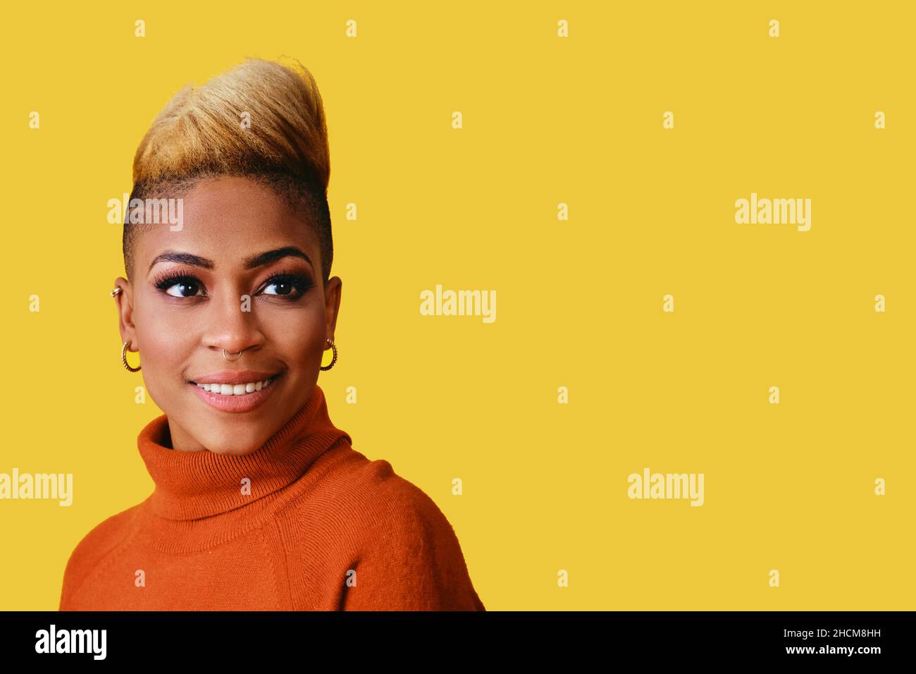 Portrait of a smiling young woman with cool hair and sweater looking at Yellow copy space Stock Photo