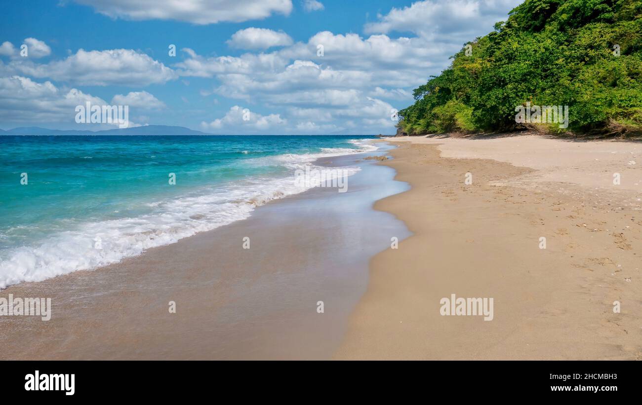 A picturesque beach scene with turquoise water, ebbing tide, wet sand, fluffy clouds, and no people. Shot in Abra de Ilog, Mindoro Island, Philippines Stock Photo