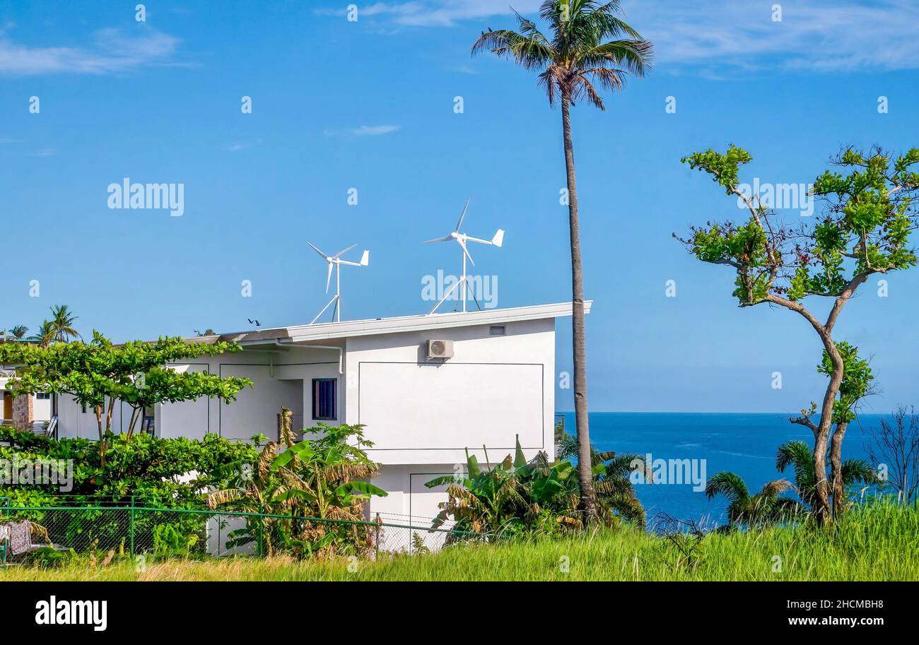 A house with two residential wind turbines installed on its roof for power generation, on Mindoro Island in the Philippines. Stock Photo