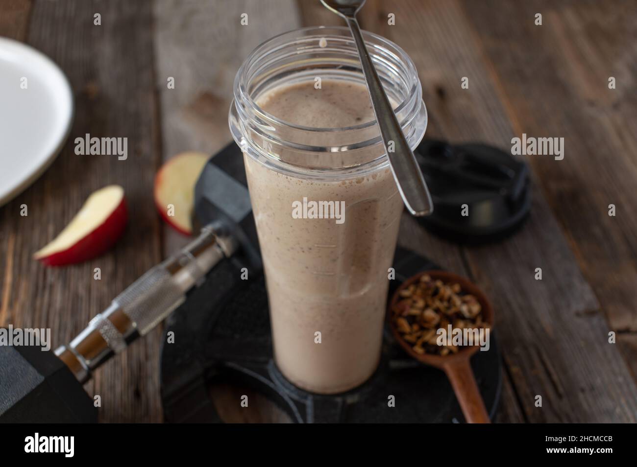 Fitness breakfast shake with whey protein powder, homemade granola and fresh fruits. Served in a shaker on a table with dumbbell Stock Photo