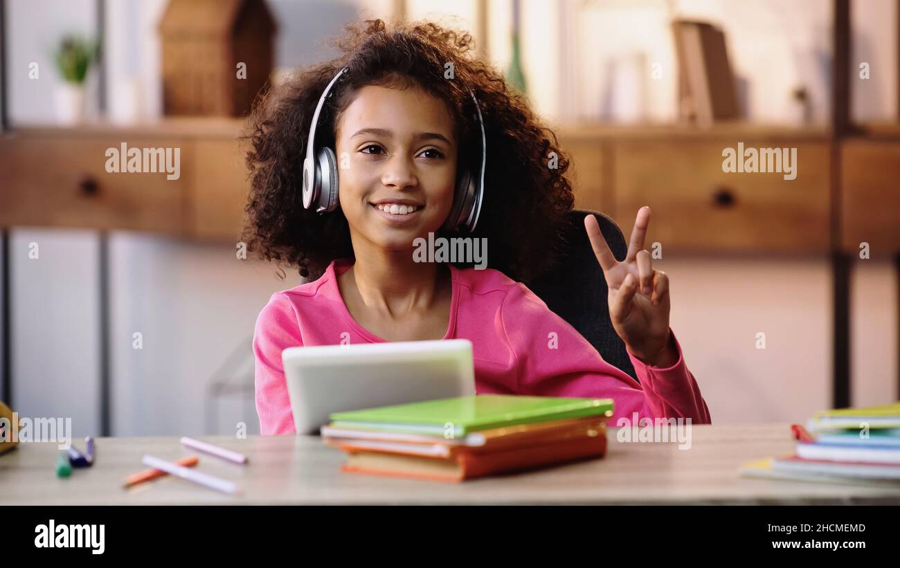 happy african american girl in headphones showing peace sign and ...