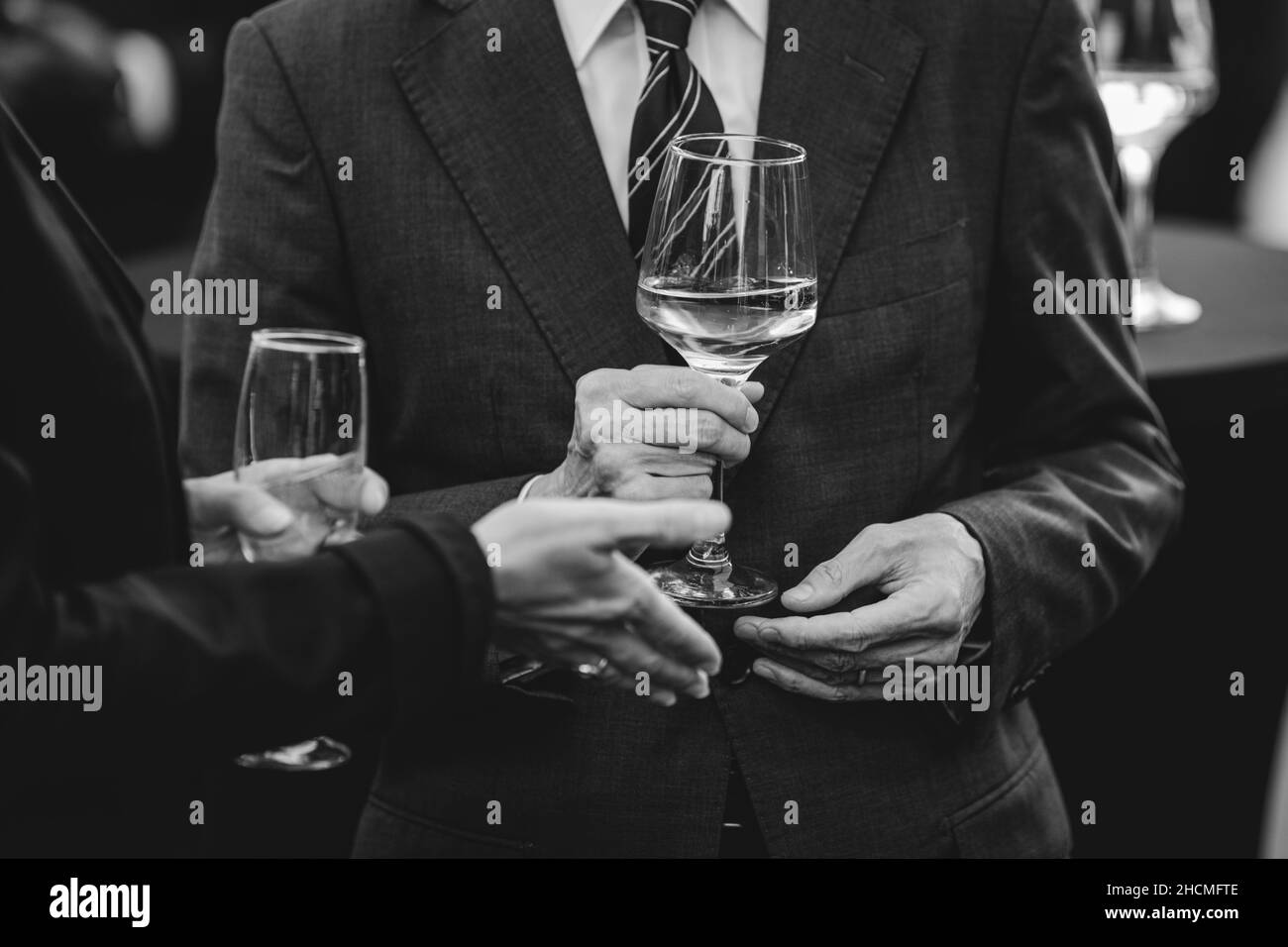 Details with a man and a woman interacting at a classy event, while holding  glasses of white wine. Stock Photo