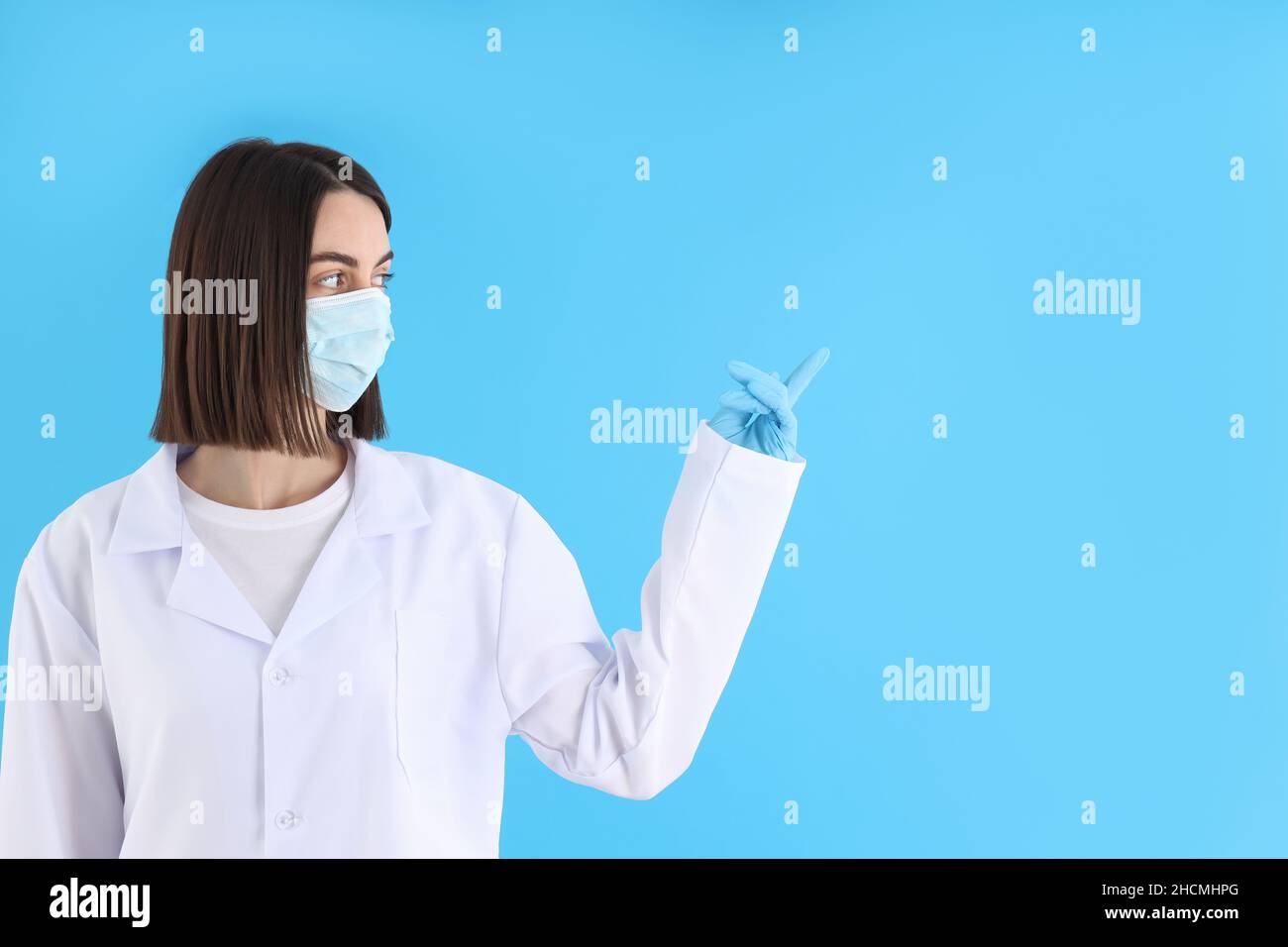 Female doctor in mask and gloves on blue background Stock Photo - Alamy