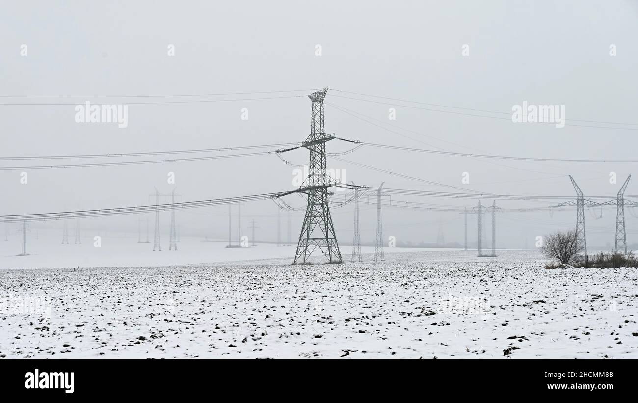 High voltage pylons in winter landscape with snow. Expensive heating in ...