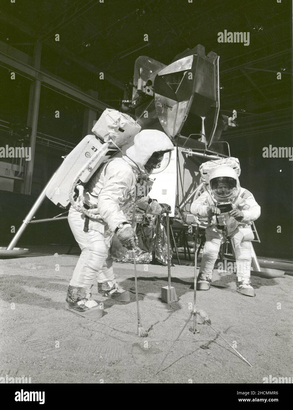 Two members of the Apollo 11 lunar landing mission participate in a simulation of deploying and using lunar tools on the surface of the Moon during a training exercise on April 22, 1969. Astronaut Buzz (Aldrin Jr. on left), lunar module pilot, uses a scoop and tongs to pick up a soil sample. Astronaut Neil A. Armstrong, Apollo 11 commander, holds a bag to receive the sample. In the background is a Lunar Module mockup. Stock Photo