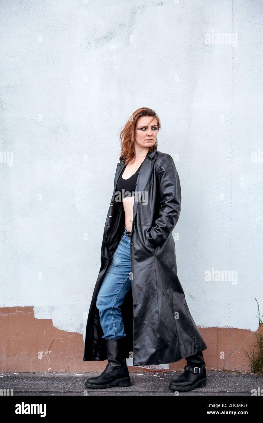 young brunette woman in jeans and black leather coat standing on the ...