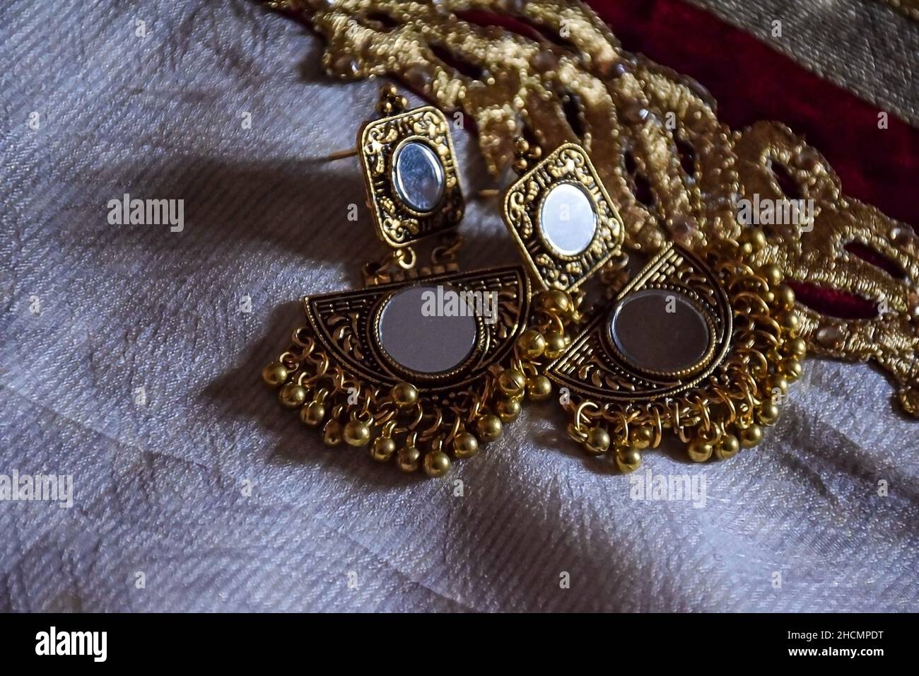 Stock photo of beautiful Indian jewelry golden mirror zumka or earring on white background.traditional Indian trendy jewelry, focus on object at Banga Stock Photo