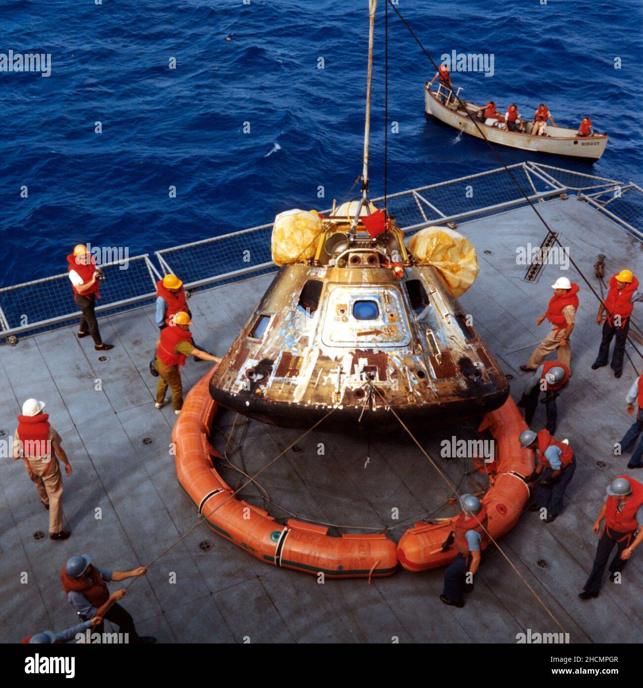 S69-21294 -- The Apollo 11 spacecraft Command Module is photographed being lowered to the deck of the U.S.S. Hornet, prime recovery ship for the historic lunar landing mission. Note the flotation ring attached by Navy divers has been removed from the capsule. Stock Photo