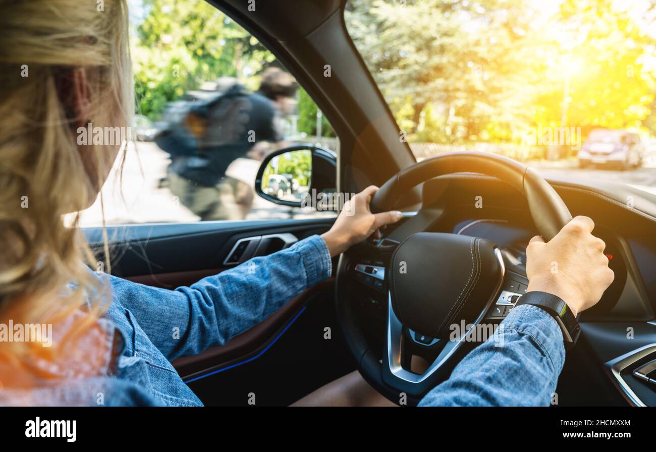 Rear view of attractive young woman in casual wear looking carefully to the road while driving a car. Stock Photo
