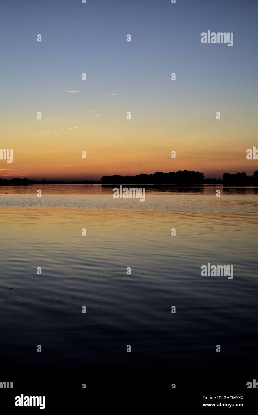 Sunset over a lake with a forest in the backdrop Stock Photo - Alamy
