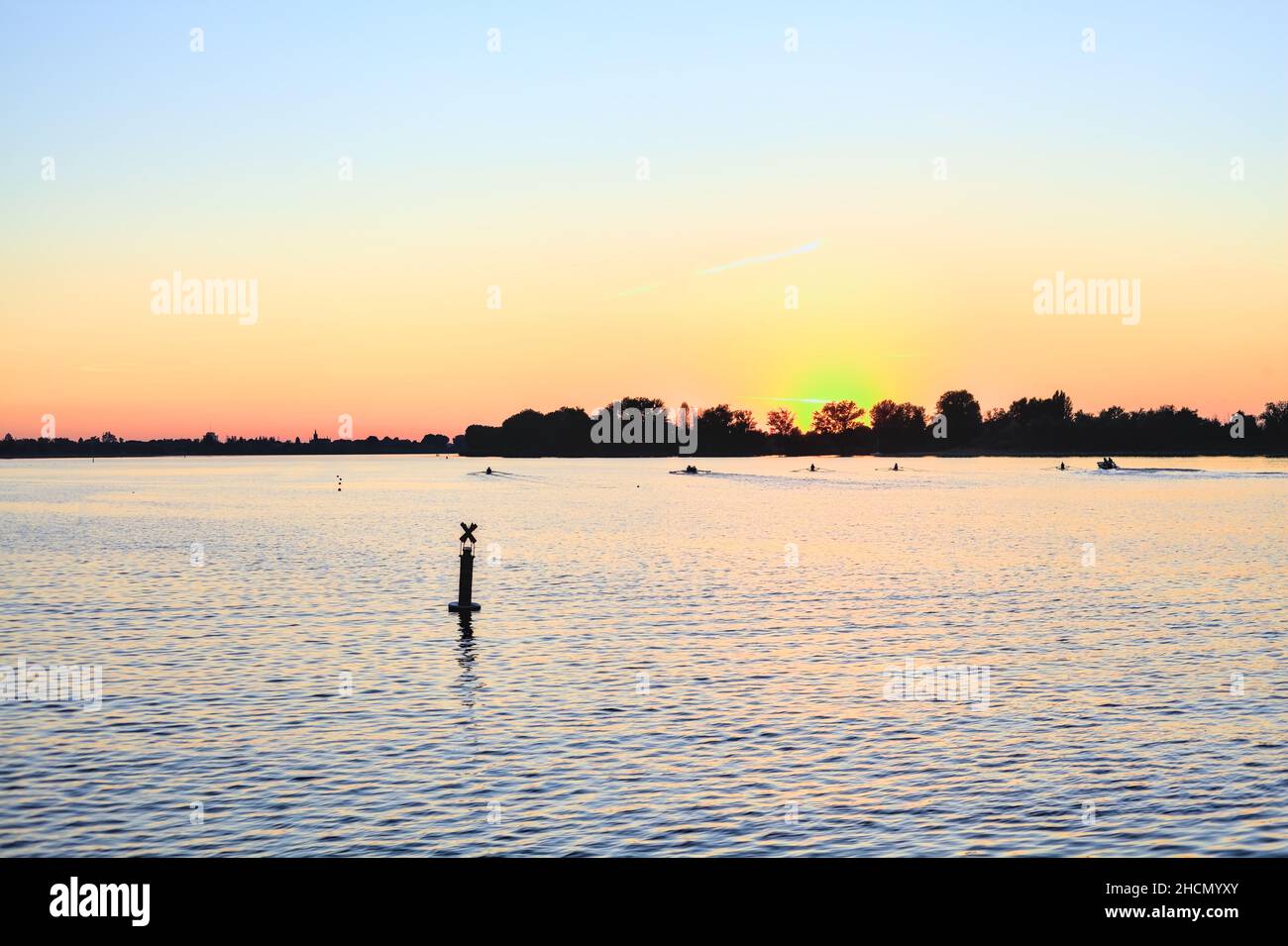 Sunset over a lake with a forest in the backdrop Stock Photo - Alamy