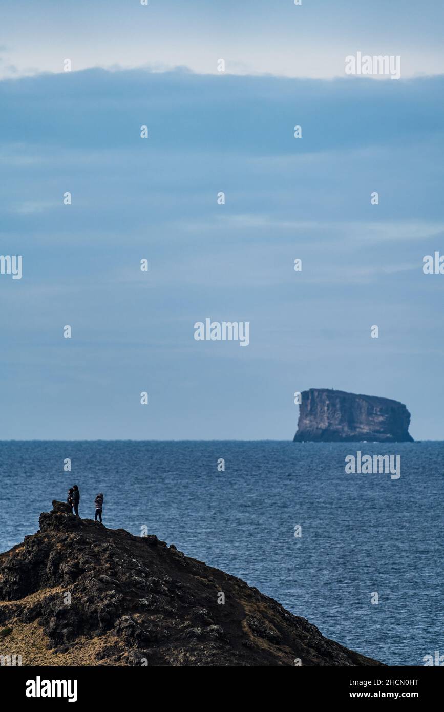 Tourists over the hill with huge islet in the background Stock Photo