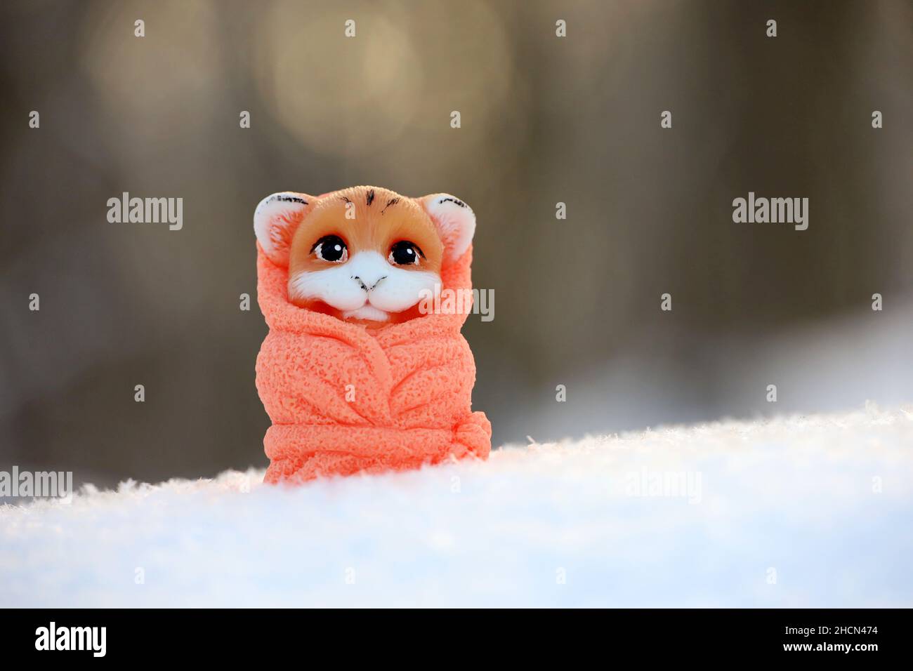 Toy tiger in snow on blurred forest background. Background for greeting card of New Year celebration, chinese 2022 year of the Tiger Stock Photo