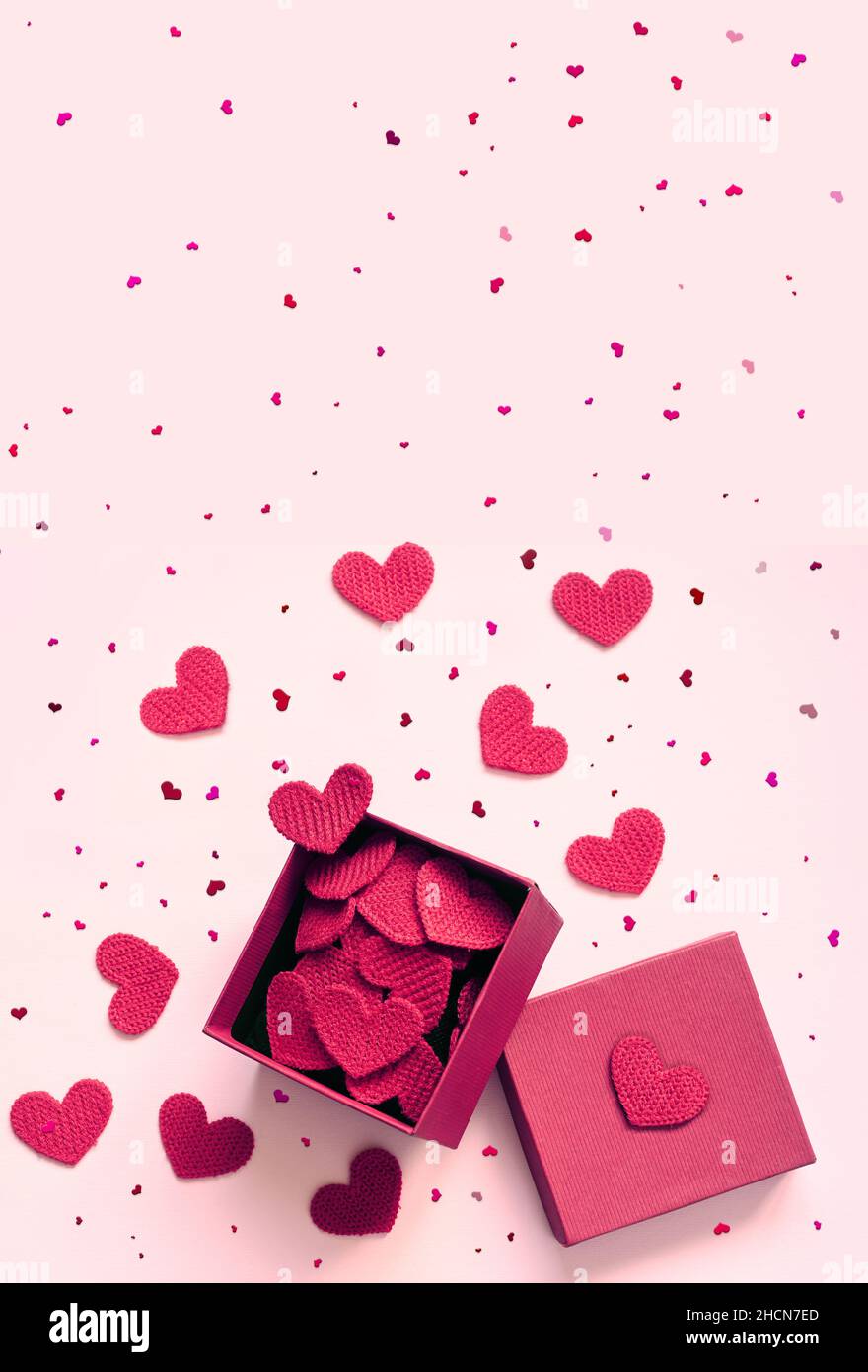 Open gift box and knitted hearts on pink background, top view. Valentines day greeting card. Flat lay style. Stock Photo