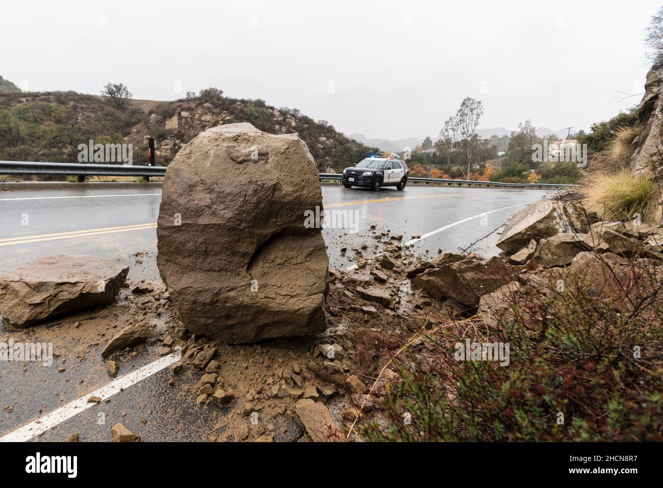 Los Angeles, California, USA - December 30, 2021:  Los Angeles Police car responding to rain storm landslide blocking traffic lane. Stock Photo