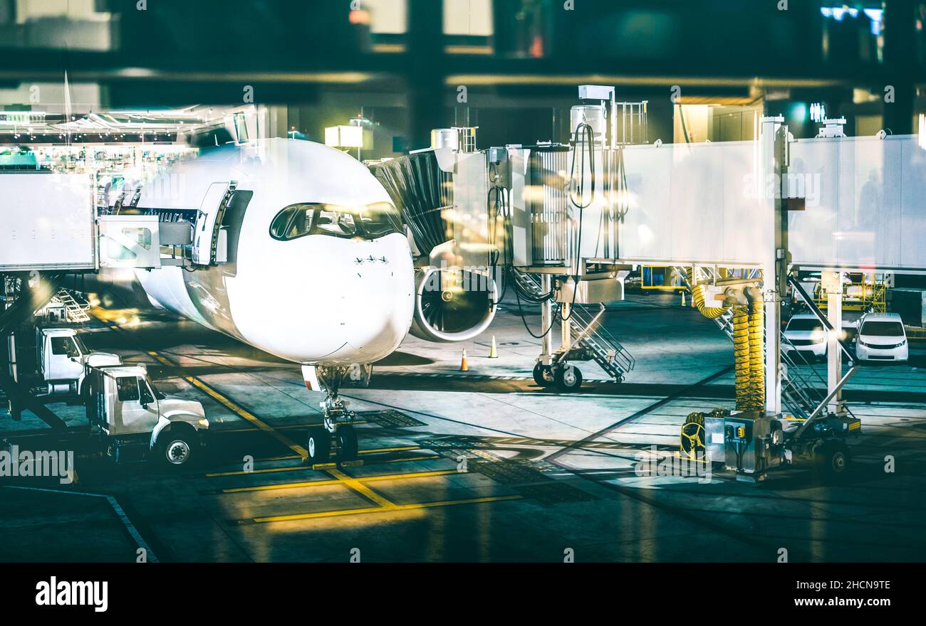 Airplane at terminal gate preparing takeoff by night - Modern international airport with boarding aircraft on nighttime Stock Photo
