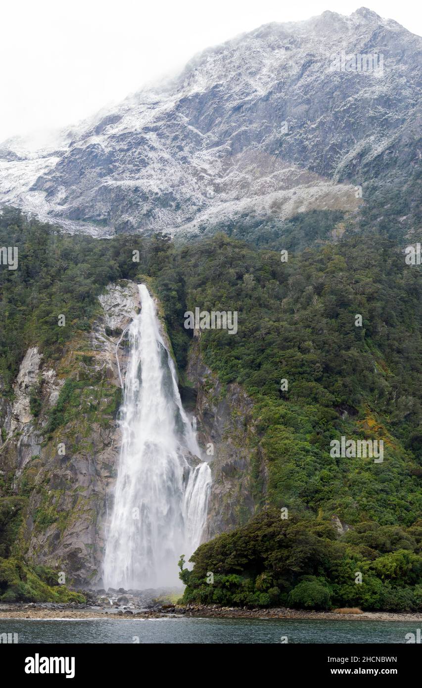 Waterfall cascading down the mountainside in Milford Sound, part of the Fiordland National Park, South Island, New Zeland Stock Photo