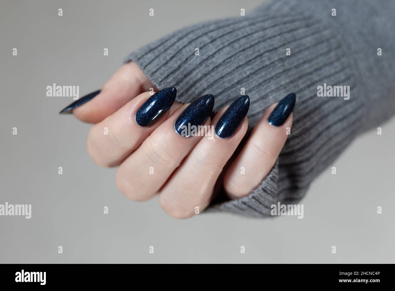 Female hand with long nails and dark blue teal manicure holds a bottle of  nail polish Stock Photo - Alamy