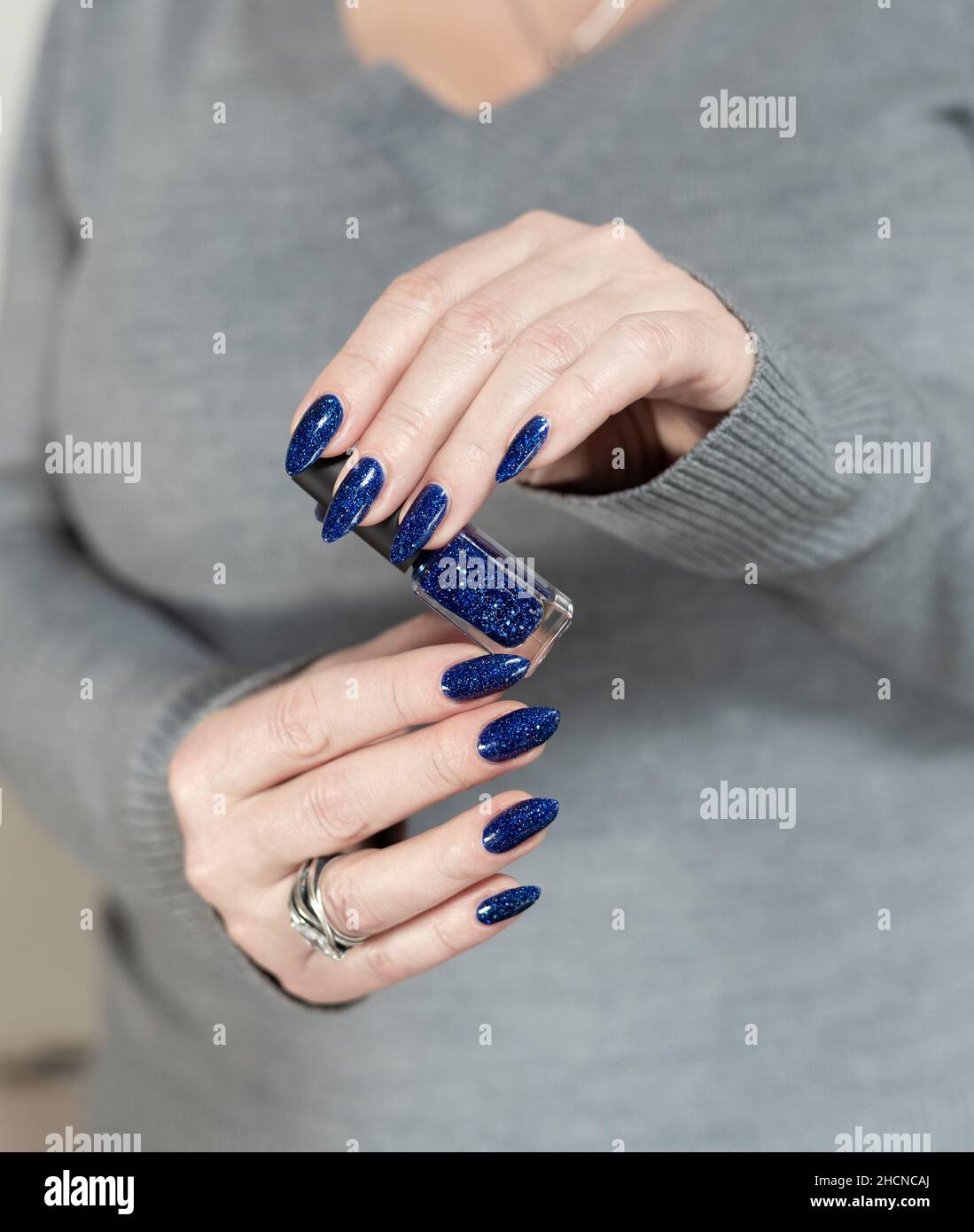 Female hand with long nails and dark blue teal manicure holds a bottle of  nail polish Stock Photo - Alamy