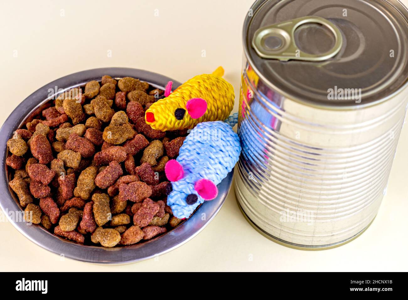Brown crunchy organic kitty kibble pieces in a bowl, toy mice and wet