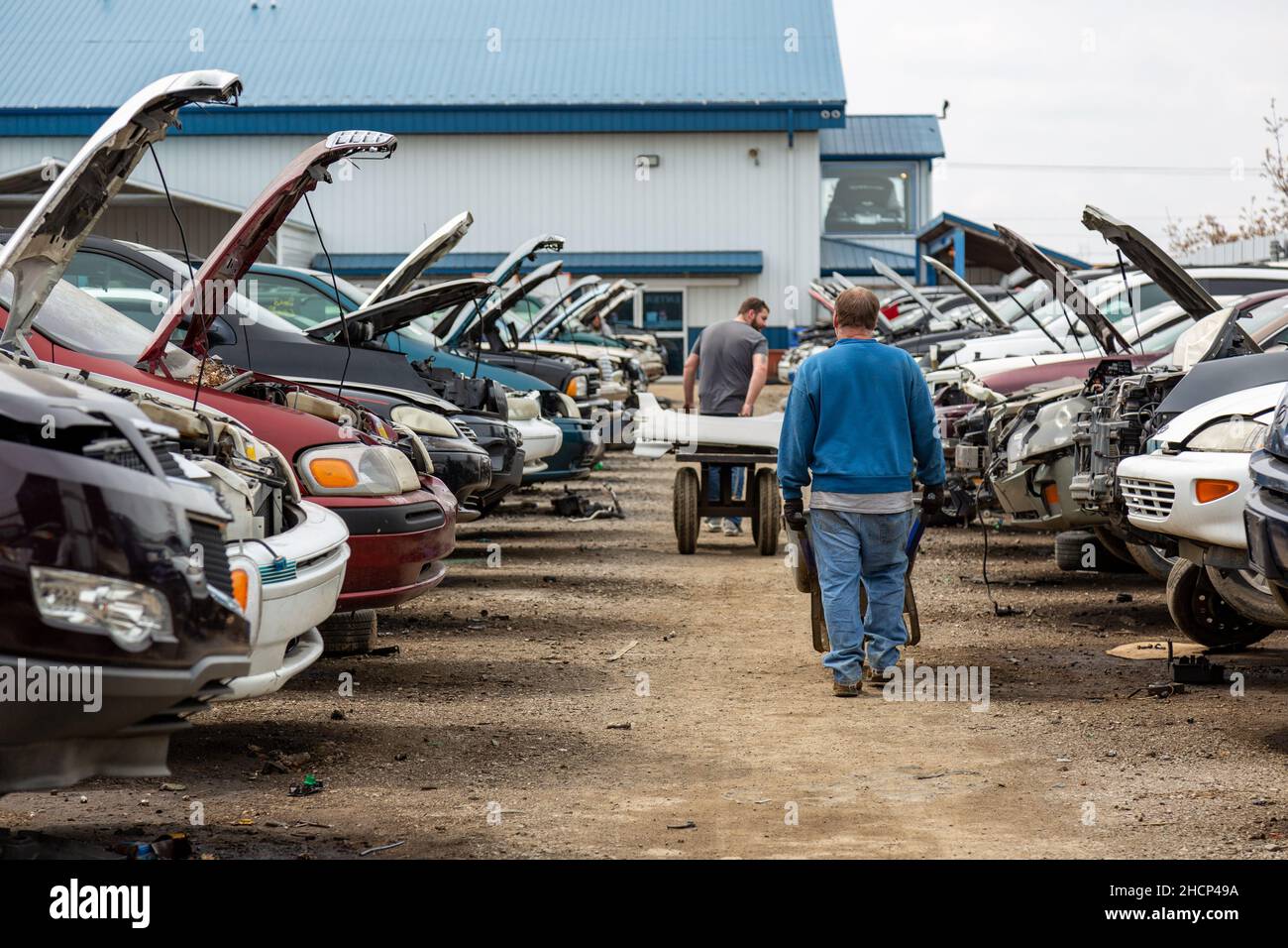 Two men push carts through an aisle in the General Motors section at the LKQ Pick Your Part auto salvage yard in Fort Wayne, Indiana, USA. Stock Photo