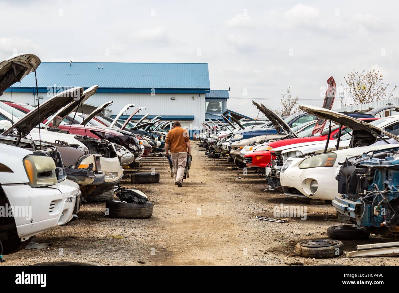 A man pushes a cart through an aisle in the General Motors section at the LKQ Pick Your Part auto salvage yard in Fort Wayne, Indiana, USA. Stock Photo