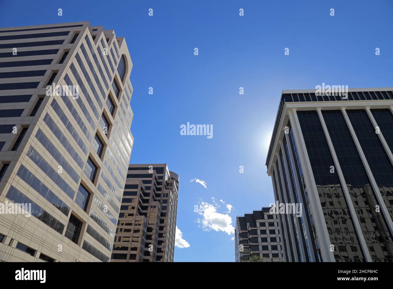Tall business buildings are shown from a street level view during the day. Stock Photo