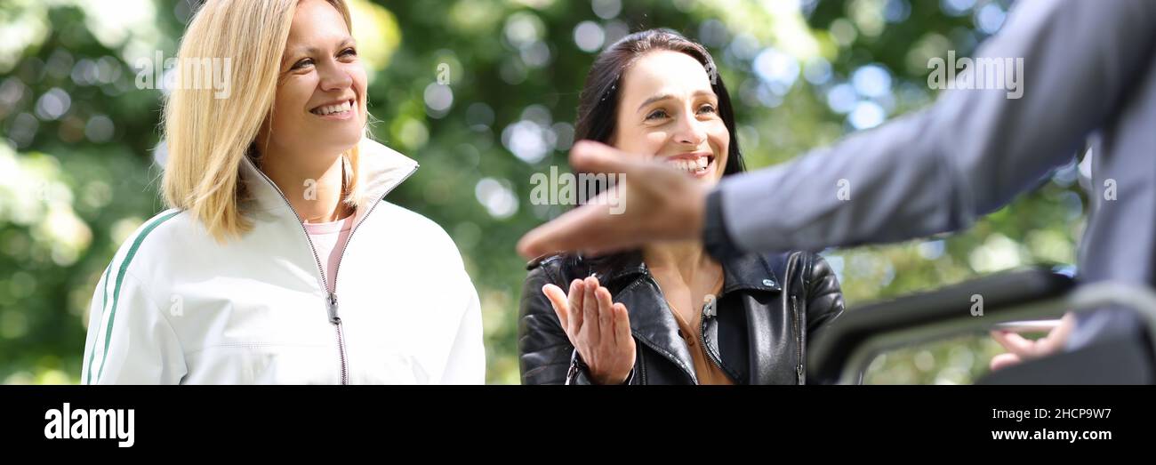 Young women and man in wheelchair laugh and chat in park Stock Photo ...