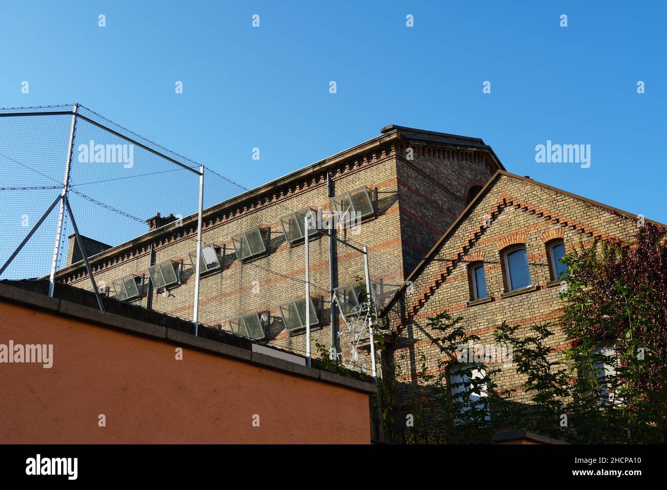 Former penitentiary or prison building surrounded by high walls and security net. Stock Photo