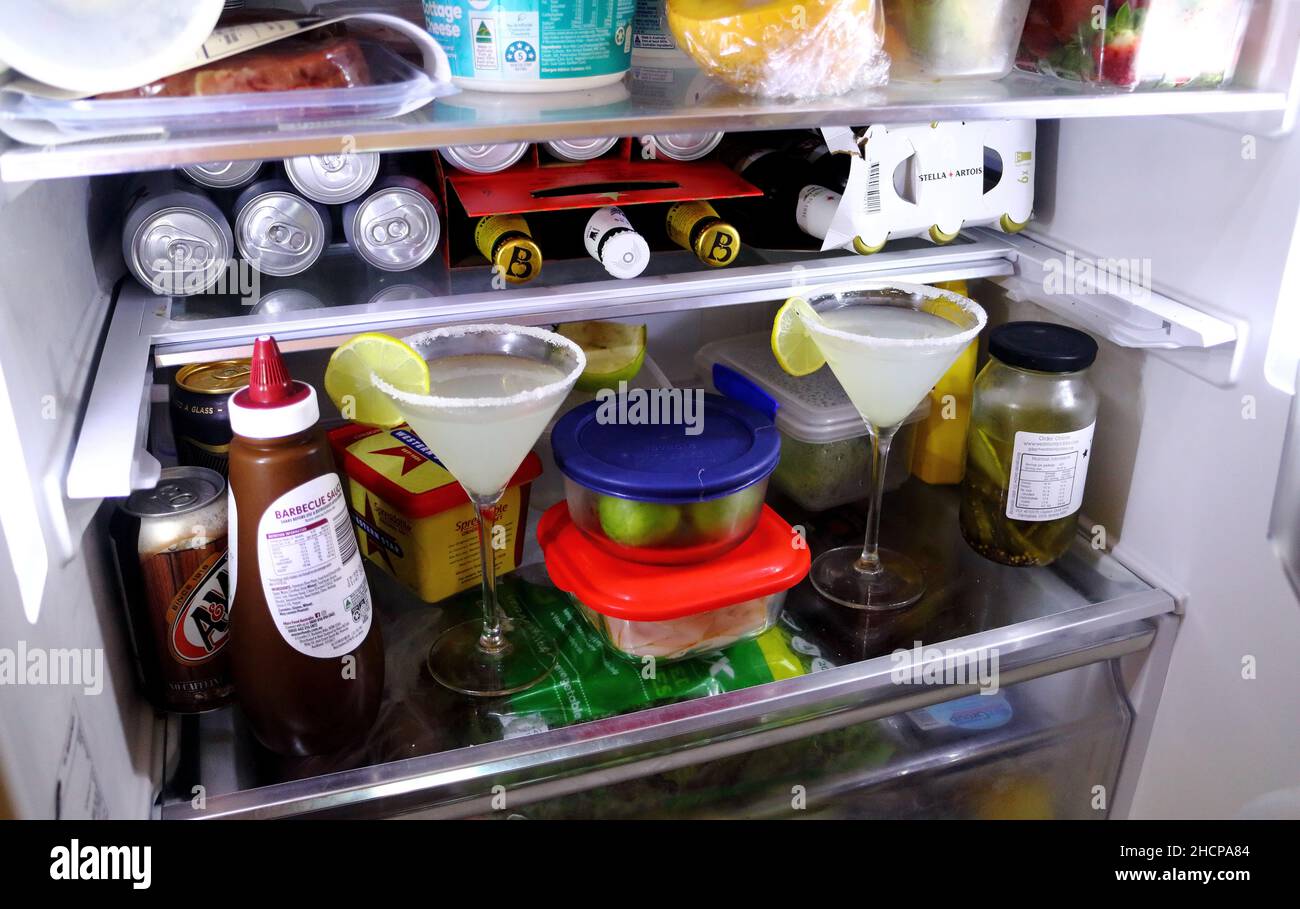Two Vodka Sidecar drinks in coctail glass chilling in a full messy fridge Stock Photo