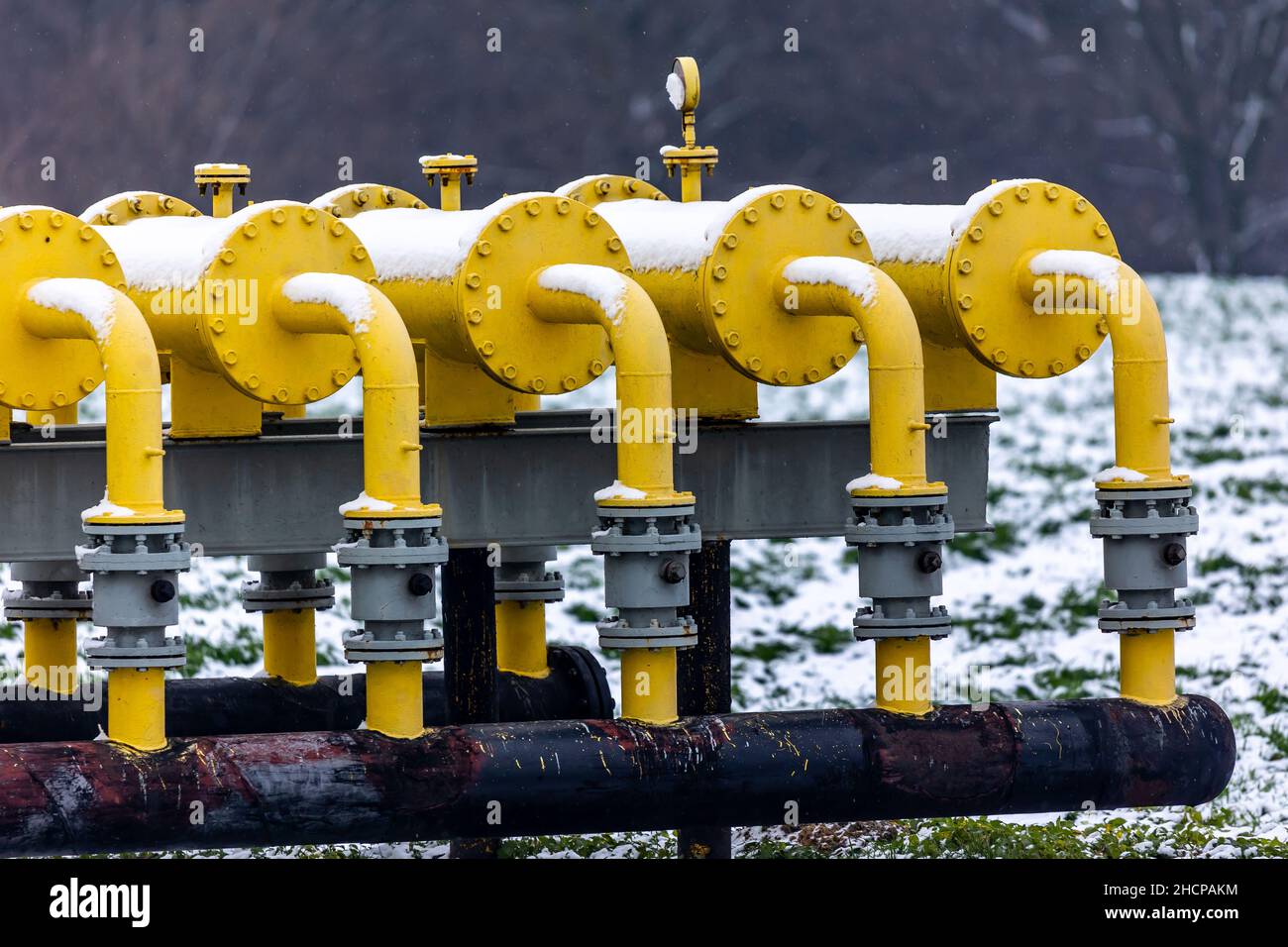 Yellow gas infrastructure elements sticking out of the ground. Winter photo of a snow-covered gas pipeline. High natural gas prices. The photo was tak Stock Photo
