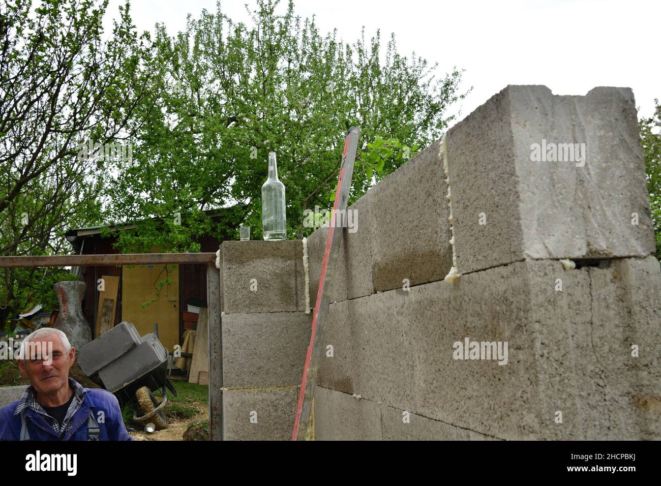 The mason builds a bottle of alkohol on the corner of the wall at the construction site as a tradition Stock Photo