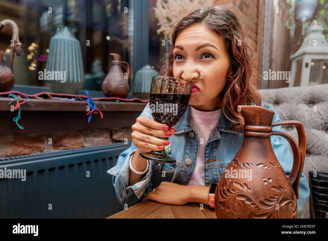 A woman sniffs wine from a glass in a restaurant. Concept sommelier and rancid spoiled drink Stock Photo