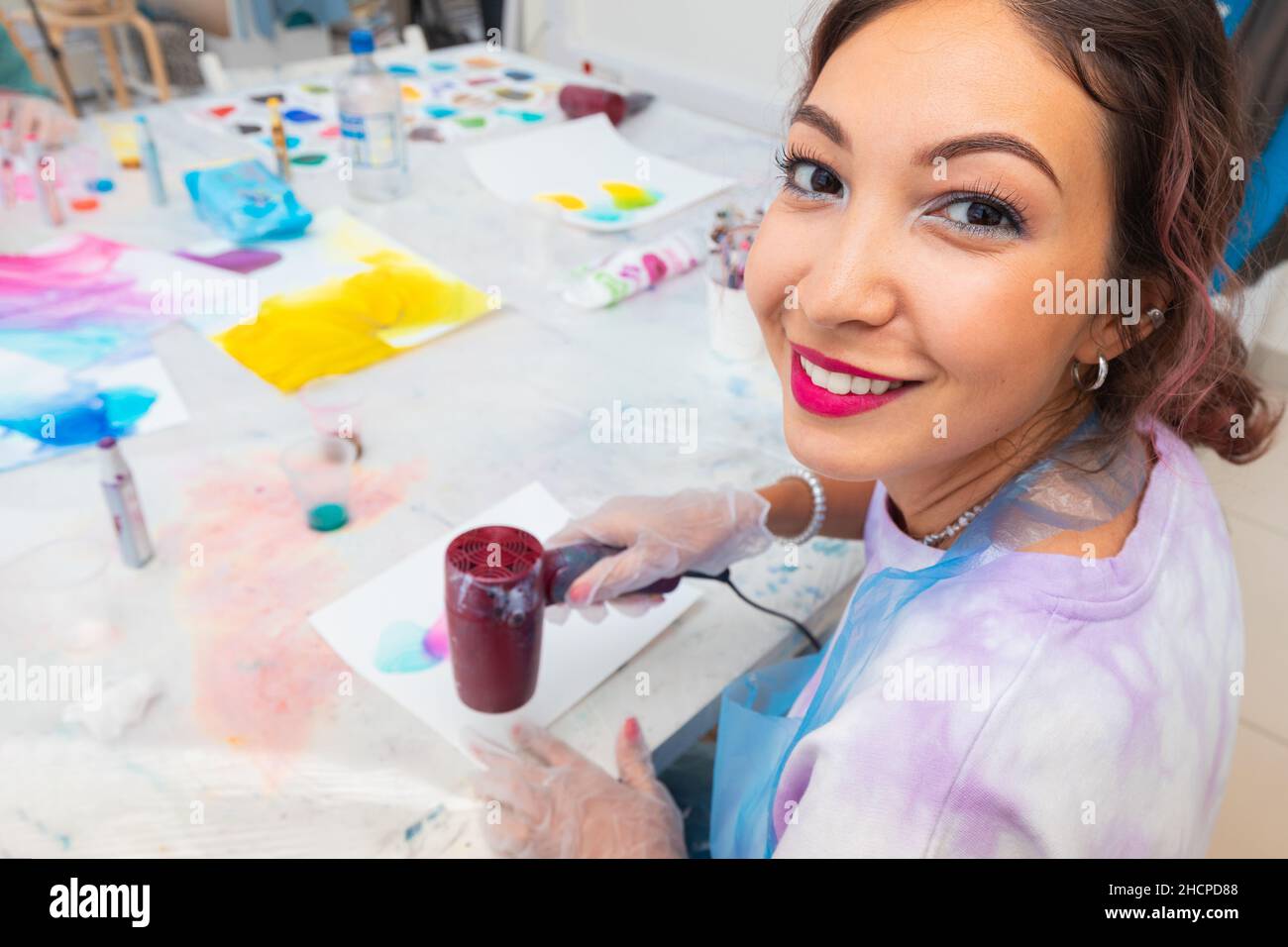 Happy woman using a trending technique of drawing with alcoholic ink