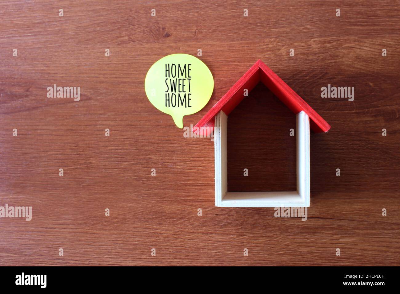 Top view image of wooden toy house and speech bubble with text HOME SWEET HOME Stock Photo