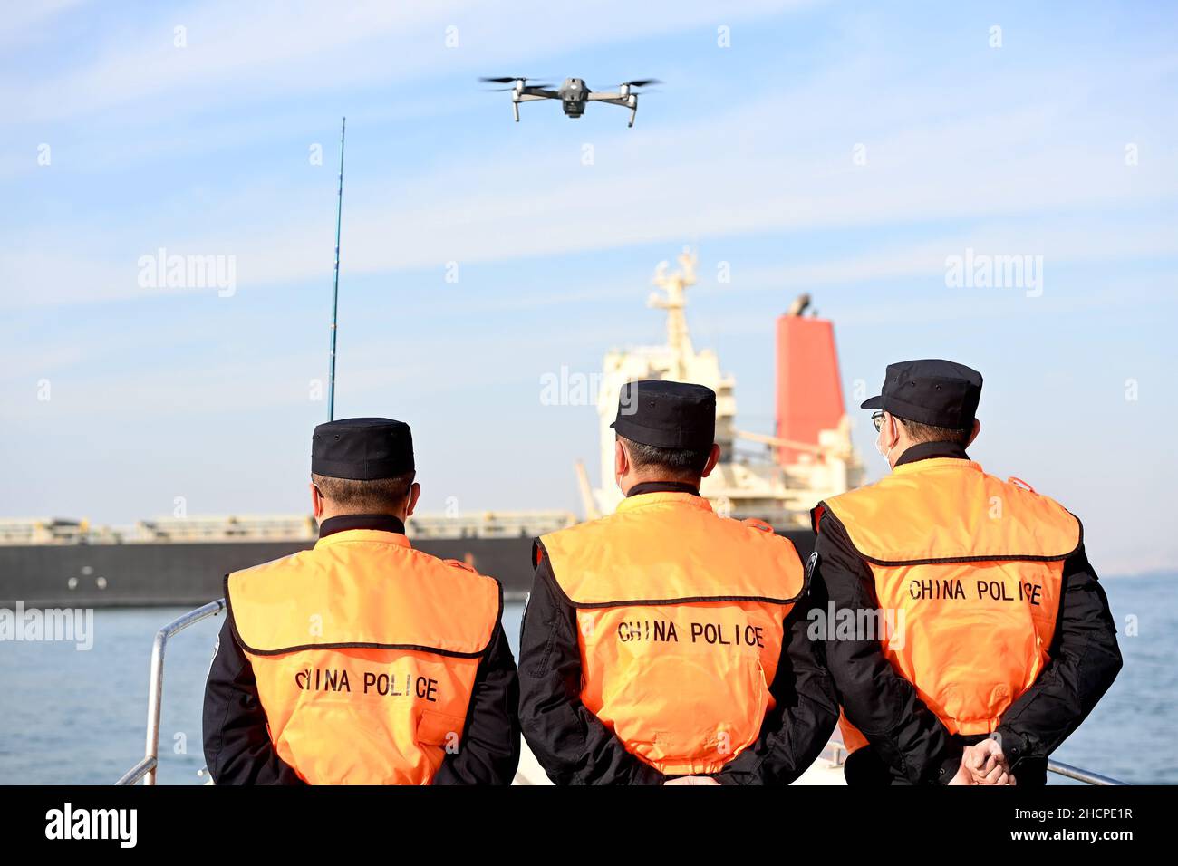 QINGDAO, CHINA - DECEMBER 31, 2021 - Police officers on duty fly a drone to inspect a berthing foreign ship at huangdao Entry-Exit border control stat Stock Photo