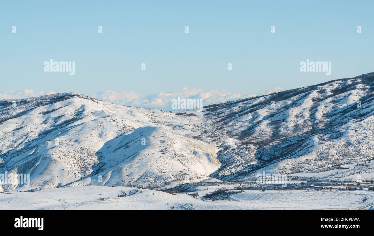 Clouds over snow capped mountains landscape Stock Photo - Alamy