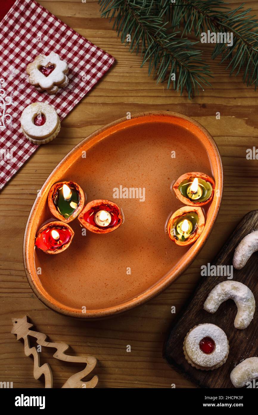 Candles made from nut shell floating on water. Christmas tradition. Decoration and christmas sweets on table Stock Photo