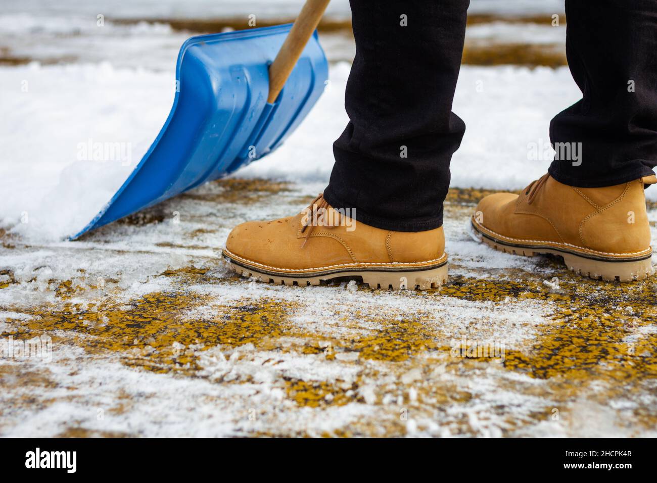 Removal snow from driveway after snowfall. Man using snow shovel on