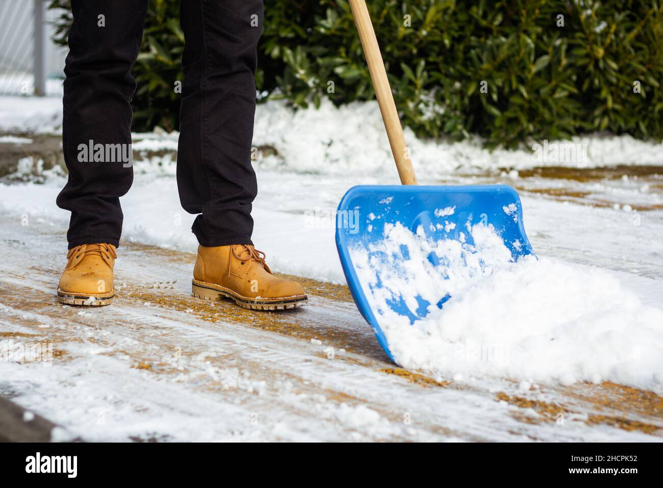 Removing snow from driveway. Man using snow shovel on street in winter